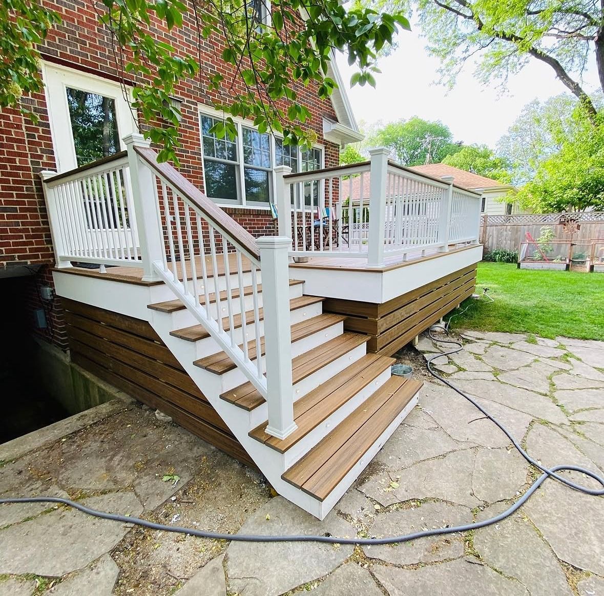 Backyard composite deck with white railing and wide stairs on a brick Chicago home